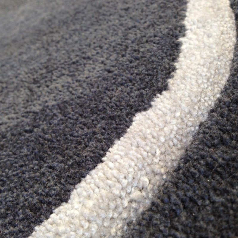 Tapis design vague avec du relief gris foncé et fines vagues en gris clair