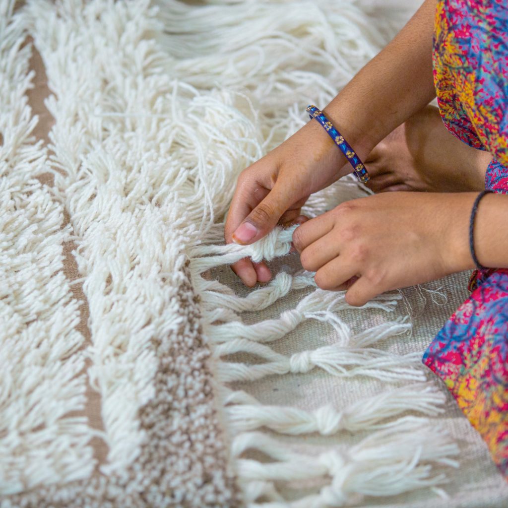 artisan qui fabrique un tapis; un facteur qui permet de déterminer le prix du tapis 